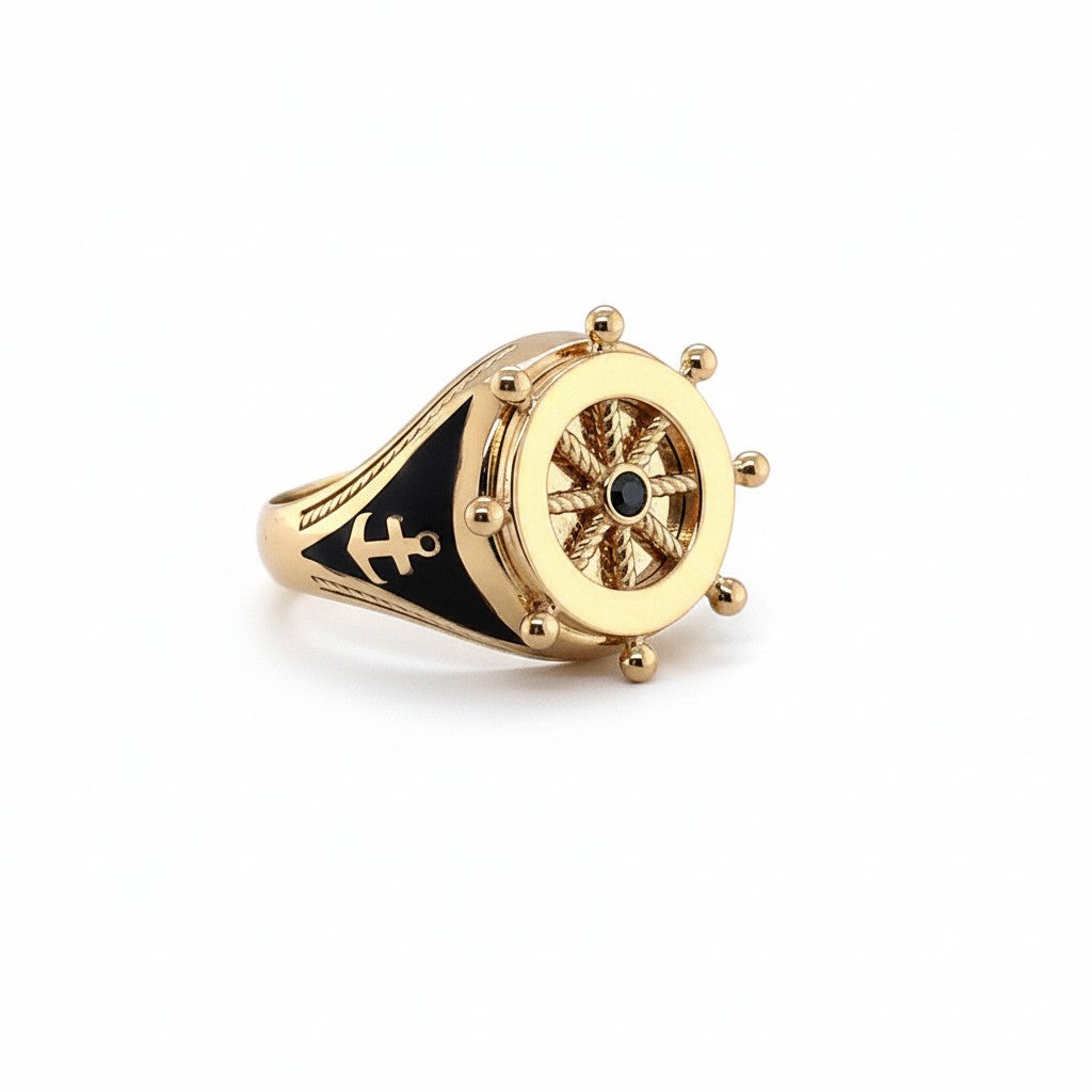 Caribbean Gems gold ring featuring a nautical ship wheel design with black enamel accents and an anchor motif.
